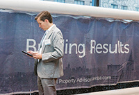 Robert Sein, St. Johns University Standing in Front of Ariel Property Advisors Banner